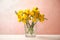 Beautiful blooming yellow freesias in glass vase on table against background
