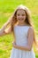 Beautiful blue-eyed girl with long blond hair in a white dress walking in the flower garden. summer bright, emotional photo