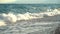 Beautiful blue foamy sea waves rolling crashing onto shore, pebble beach with clear azure water