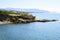 Beautiful blue lagoon with clear sea water and a pebble beach and rocks, deserted, with a view of the city in the distance.