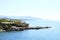 Beautiful blue lagoon with clear sea water and a pebble beach and rocks, deserted, with a view of the city in the distance.