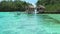 Beautiful blue lagoon with some bamboo huts, kordiris homestay, palm-tree in front, Gam Island, West Papuan, Raja Ampat