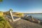 Beautiful blue lake with an empty bench on its sandy and grassy shore