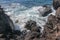 Beautiful blue sea and a beach with huge stone blocks. Danger sea wave crashing on rock coast with spray and foam. Stony coast