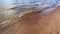 Beautiful blue sea with small waves running onto wet sand.