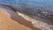 A beautiful blue sea with small waves running onto wet sand.