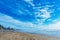 Beautiful blue sky with light clouds over empty sandy beach with random foot steps. Ocean waves and coastline with residential