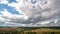 Beautiful blue sky with puffy white clouds over luscious green landscape, time lapse of clouds flying over flat terrain