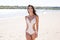 Beautiful boho styled girl wearing white crochet swimsuit at the beach in sunlight