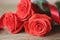 Beautiful bouguet red roses with green leaves and red satin ribbon lying on a wooden table. Macro.. Macro.