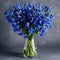 Beautiful bouquet of bluebells in white clear glass vase on light grey background. Bouquet of fresh bluebells flowers in a vase