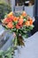 Beautiful bouquet in coral orange colors of roses, tulips, Jatropha multifida, Carthamus tinctorius and other plants in the male