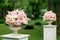 A beautiful bouquet of flowers in a stone vase stands on a column on a green background. Decor for the wedding ceremony