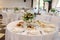 Beautiful bouquet in a glass vase on a dining table. White napkin on a white empty plate on a dining table. Table setting.