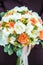 A beautiful bouquet of mixed flowers in the hand of the groom in a suit. Wedding bouquet of fresh flowers for the bride