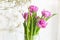 A beautiful bouquet of pink tulips and gypsophila in a vase by the window.