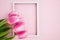 Beautiful bouquet of pink tulips and white vertical frame on pink background. Flatlay. Close-up. Top view. Copy space