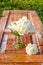 Beautiful bouquet of roses with drops in green glass vase on old wooden table