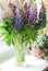 Beautiful bouquet of summer lupines on a sunny window.