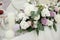 Beautiful bouquet of white and purple flowers in a vase, and eucalyptus greenery, candle on holiday table.