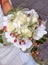 Beautiful bouquet of white roses with orchids and red berries held by a bride`s hand on her wedding day. Roses, Orchidaceae.