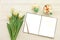 Beautiful bouquet of white tulips, empty open notebook, silver pen, cup of cappuccino, makaroons on the white wooden background