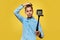 Beautiful boy blogger makes a selfie or video on a compact camera with the monopod. Yellow background. Copy space