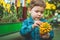 Beautiful boy playing with plant succulents in the retail store. Gardening In Greenhouse