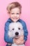 Beautiful boy with Royal Standard Poodle. Studio portrait over pink background. Concept: friendship between boy and his dog