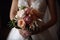 Beautiful bridal bouquet in the hands of the bride, closeup, bride holding a beautiful wedding bouquet close to her chest, AI