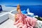Beautiful bride blonde female model in amazing wedding dress poses on the island of Santorini in Greece