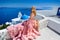 Beautiful bride blonde female model in amazing wedding dress poses on the island of Santorini in Greece