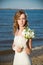 Beautiful bride with a bouquet of calla lilies on coast of river