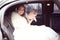 Beautiful bride with bridal bouquet in car on wedding day