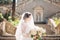 Beautiful bride covered with a veil with bridal bouquet on the stairs of the Nativity of the Blessed Virgin Mary church