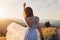 Beautiful bride dancing in blue wedding dress with embroidery and bare back in mountains at sunset. Woman holds flowers