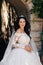 beautiful bride with dark hair in luxurious wedding dress in elegant villa