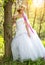 Beautiful bride , flower tiara on her head , relying on the tree