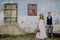 Beautiful bride and groom in front of old shabby house.