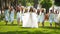 Beautiful bride and her pretty bridemaids in pale blue dresses walking in the park cheering waving hands. Woman with