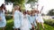 Beautiful bride and her pretty bridemaids in same pale blue dresses posing cheering waving hands in a park. Woman with