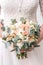 Beautiful bride is holding a wedding colorful bouquet. Beauty of colored flowers. Close-up bunch of florets. Bridal accessories. F
