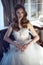 Beautiful bride in luxurious A-line wedding dress sitting in the vintage arm chair