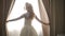 Beautiful bride opens the curtains in the dark