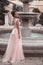 Beautiful bride in pink wedding dress. Outdoor romantic portrait of attractive brunette woman with hairstyle in prom dress with