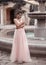 Beautiful bride in pink wedding dress. Outdoor romantic portrait of attractive brunette woman with hairstyle in prom dress with