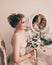 Beautiful bride sitting in front of mirror .