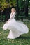 The Beautiful bride is spinning around herself in dance. woman is posing in fluttering dress outdoors. Artwork