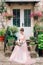 beautiful bride in tender wedding dress with bridal bouquet is sitting on the porch of the house in Perast