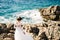 Beautiful bride in tender wedding dress on the rocky beach of the Mamula island